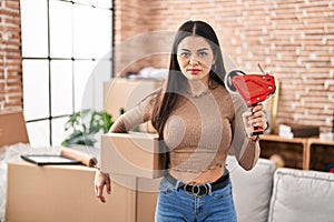 Young woman moving to a new home packing boxes clueless and confused expression