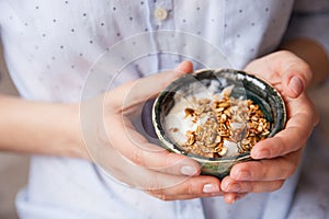 Young woman with muesli bowl. Breakfast cereals with nuts, pumpkin seeds, oats and Yogurt in bowl