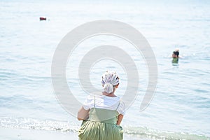 Young woman with multi-colored dreadlocks stands on the beach