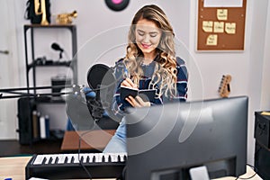 Young woman musician composing song at music studio