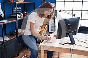 Young woman musician holding trumpet composing song at music studio