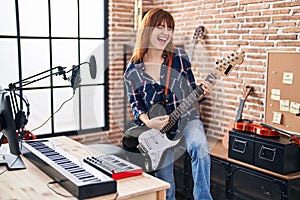 Young woman musician playing electric guitar at music studio
