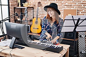 Young woman musician playing piano keyboard at music studio