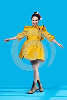 Young woman in a mustard dress standing with legs crossed