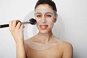 Young woman naked shoulders clean skin applying make up for a evening date in front of a camera. Space for text. photo