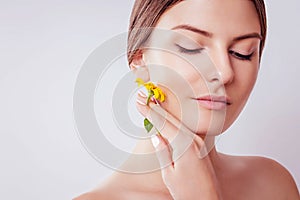 Young woman with natural makeup holding a flower. Organic cosmetics concept