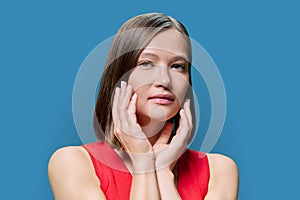 Young woman with natural makeup, with trendy nose piercing jewelry on blue background