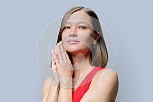 Young woman with natural makeup, with trendy nose piercing jewelry on gray background