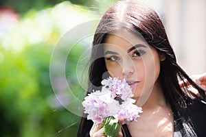 Young woman near blossom park. Spring girl. Woman on spring blooming tree. Beautiful young woman in summer style outfit