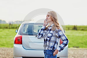 Young woman near a broken car calling for help