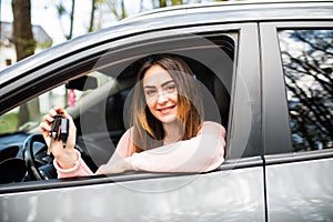 Young woman near the car with keys in hand while buying car