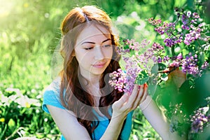 Young woman near the lilac bush in the spring park