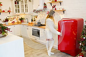 Young woman near red fridge in christmas decorated kitchen