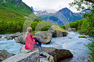 The young woman near the river which is located near path to the Briksdalsbreen Briksdal glacier. Norway