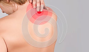 Young woman with neck pain, massaging her shoulder