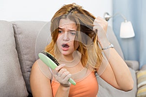 Young woman is nervous because her hair suffers from avitaminosis