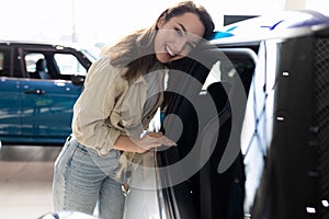 young woman next to a new car in a car dealership