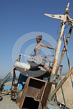 Young woman with a nice dress standing on an old boat