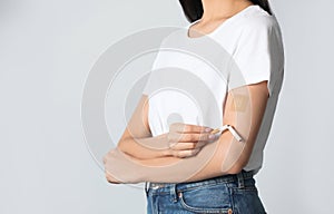 Young woman with nicotine patch and cigarette on grey background, closeup