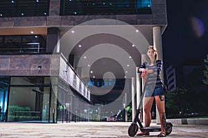 Young woman at night on a scooter in the busines center photo
