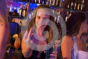 Young woman in nightclub beckoning to camera