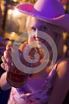 Young woman in nightclub holding drink to camera