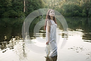 Young woman in nightie is standing in the river