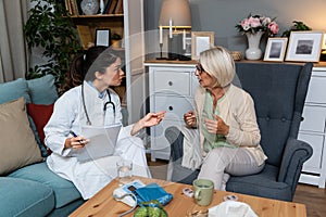 Young woman nurse doctor gp holding stethoscope examining old senior 60s grandma patient check heartbeat at homecare checkup