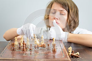 Young woman nurse doctor playing chess checkmate thinking game pieces.