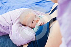 Young woman nursing and feeding baby at home