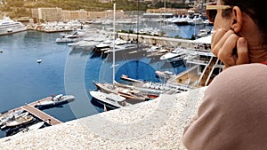 Young woman observing yachts in port, dreaming of oligarch and rich life photo