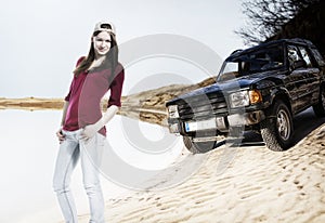 Young woman with off road car on the sand dune