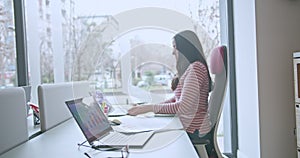 Young woman in the office focused on business growth, revenue and profit analysis on her computer with paperwork around