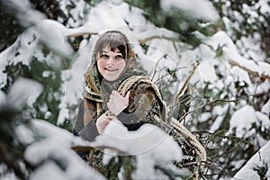 A young woman in old clothes stands with brushwood in a winter forest. character from the fairy tale