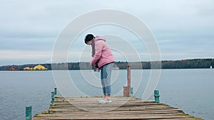 Young woman is on old pier. She looks at camera and laughs. Great day in autumn.