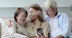 Young woman and older parents using cellphone at home