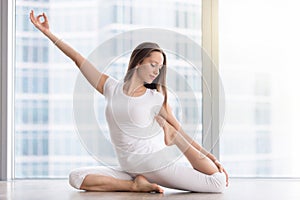 Young woman in One Legged King Pigeon exercise, floor window