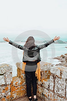 Young woman with open arms in a fortress on the sea photo