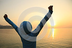 Young woman open arms on sunrise beach