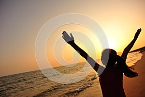 Young woman open arms on sunrise beach