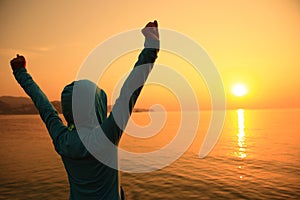 Young woman open arms on sunrise beach