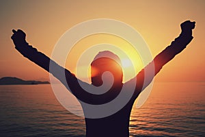 Young woman open arms on sunrise beach