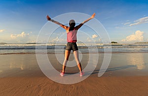 young woman open arms on sunrise seaside beach