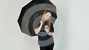 Young woman openes black umbrella on white background photo