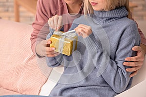 Young woman opening gift box from her boyfriend at home, closeup