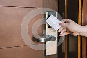 Young woman opening hotel room electronic lock with key card