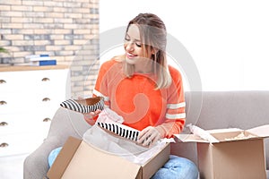 Young woman opening parcel on sofa