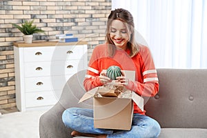 Young woman opening parcel on sofa