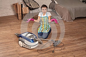 Young woman opening vacuum cleaner, possible failure. Houseworking in home.