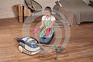 Young woman opening vacuum cleaner, possible failure. Houseworking in home.